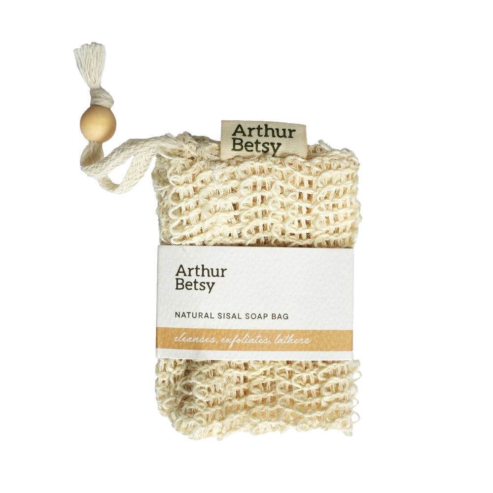 Arthur Betsy natural sisal soap bag with a wooden bead tassel and paper label, shown on a plain white background. Reusable exfoliating soap pouch made from natural sisal fibres derived from the agave plant—an eco-conscious alternative to synthetic materials.