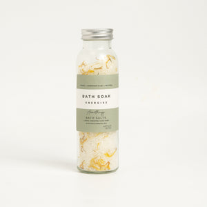 A glass bottle containing bath salts with textured recylable labels, labeled 'BATH SALTS energise'. self care gifts