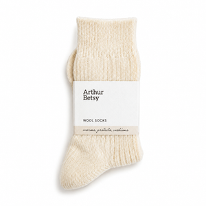 A single cream-colored knit wool sock with a white paper band label reading 'Arthur Betsy WOOL SOCKS' on a clean white background. Arthur Betsy luxury wool-blend socks in Cold Cream, designed for softness, warmth and comfortable everyday wear.