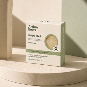 Arthur Betsy Energise Body Bar box in a minimalist cream and sage green design, displayed on a textured beige stone pedestal with soft, natural shadows. Artisan cold-process soap made in Staffordshire with plant-based oils, moisturising glycerin and pure essential oils, presented in minimal recyclable packaging.