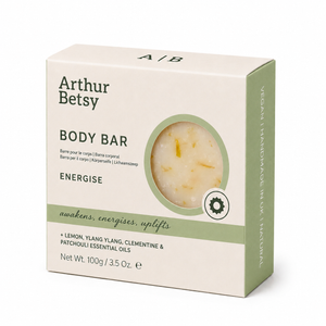 Arthur Betsy Energie Body Bar soap in a cream-colored cardboard box with sage green accents, featuring a circular window showing the pale yellow soap bar inside. Arthur Betsy 100g handmade body soap with lemon, clementine, ylang ylang and patchouli essential oils, hand-poured in Staffordshire.