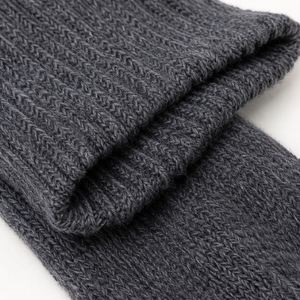 A close-up of a folded dark gray ribbed knit fabric, showing the detailed texture and weave pattern on a white background. Soft blue wool socks made from alpaca wool, nylon and spandex—a luxurious winter accessory and thoughtful self-care gift.