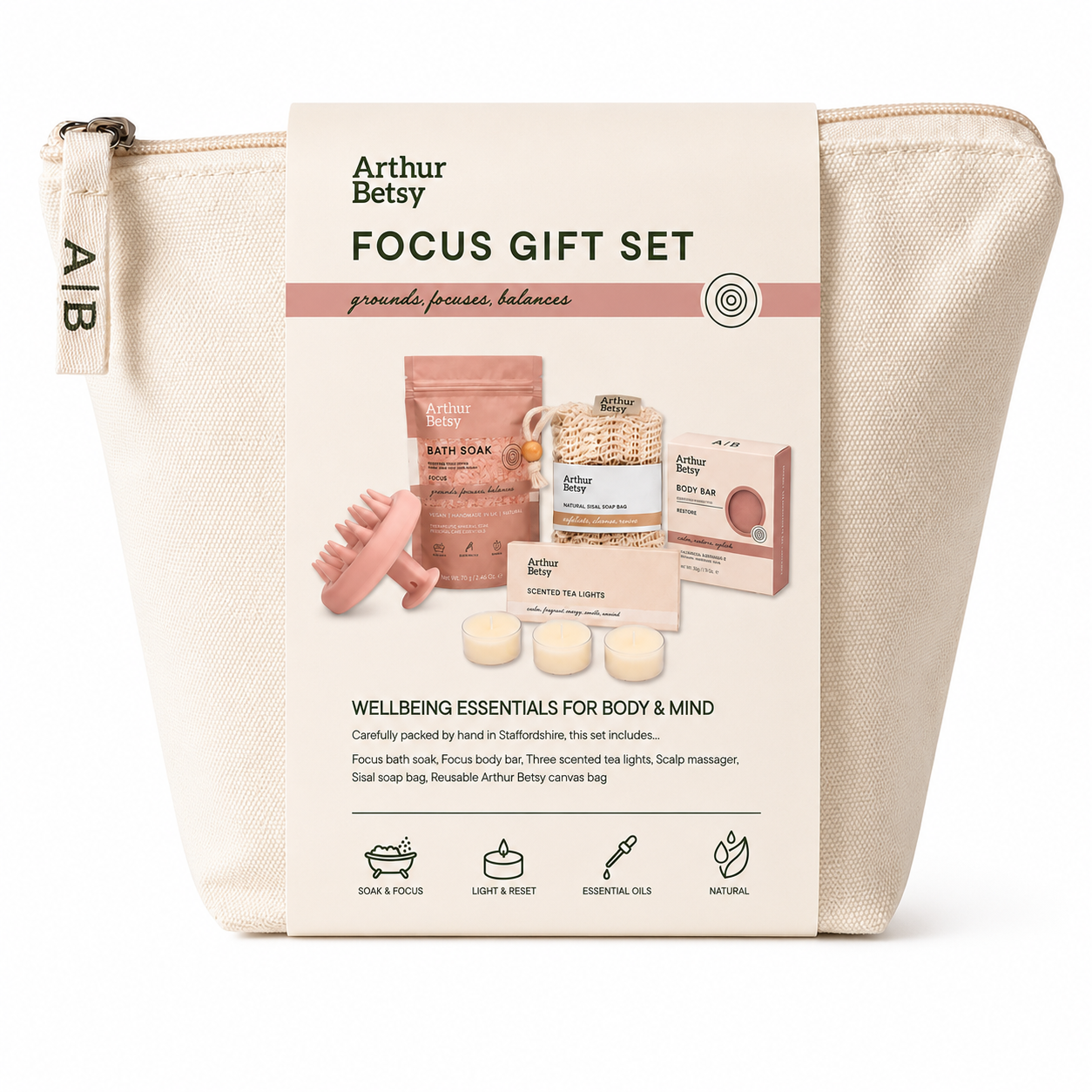 An Arthur Betsy Focus Gift Set in a cream-colored canvas zip pouch with a printed front label. The set includes bath soaks, a shower steamer, a massage tool, and soap bars, all neatly packed inside the pouch against a clean white background. Arthur Betsy Focus self-care gift set with bath soak, soap, three scented tea lights, scalp massager and natural sisal soap bag in a reusable canvas bag.