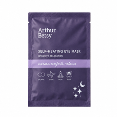 Arthur Betsy Self-Heating Eye Mask in a dark purple stand-up pouch with white text and a light purple horizontal band across the center, shown on a plain white background. Arthur Betsy self-heating eye mask providing around 20 minutes of gentle, soothing warmth to relax tired eyes and encourage rest.